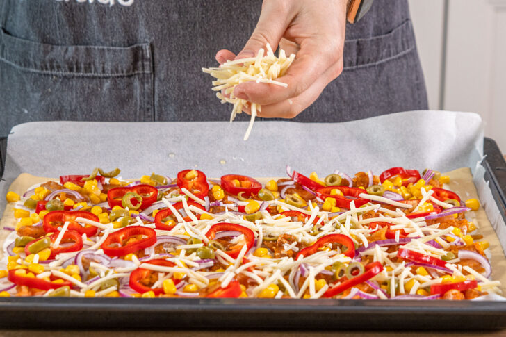 Gyros-Pizza mit Käse belegen