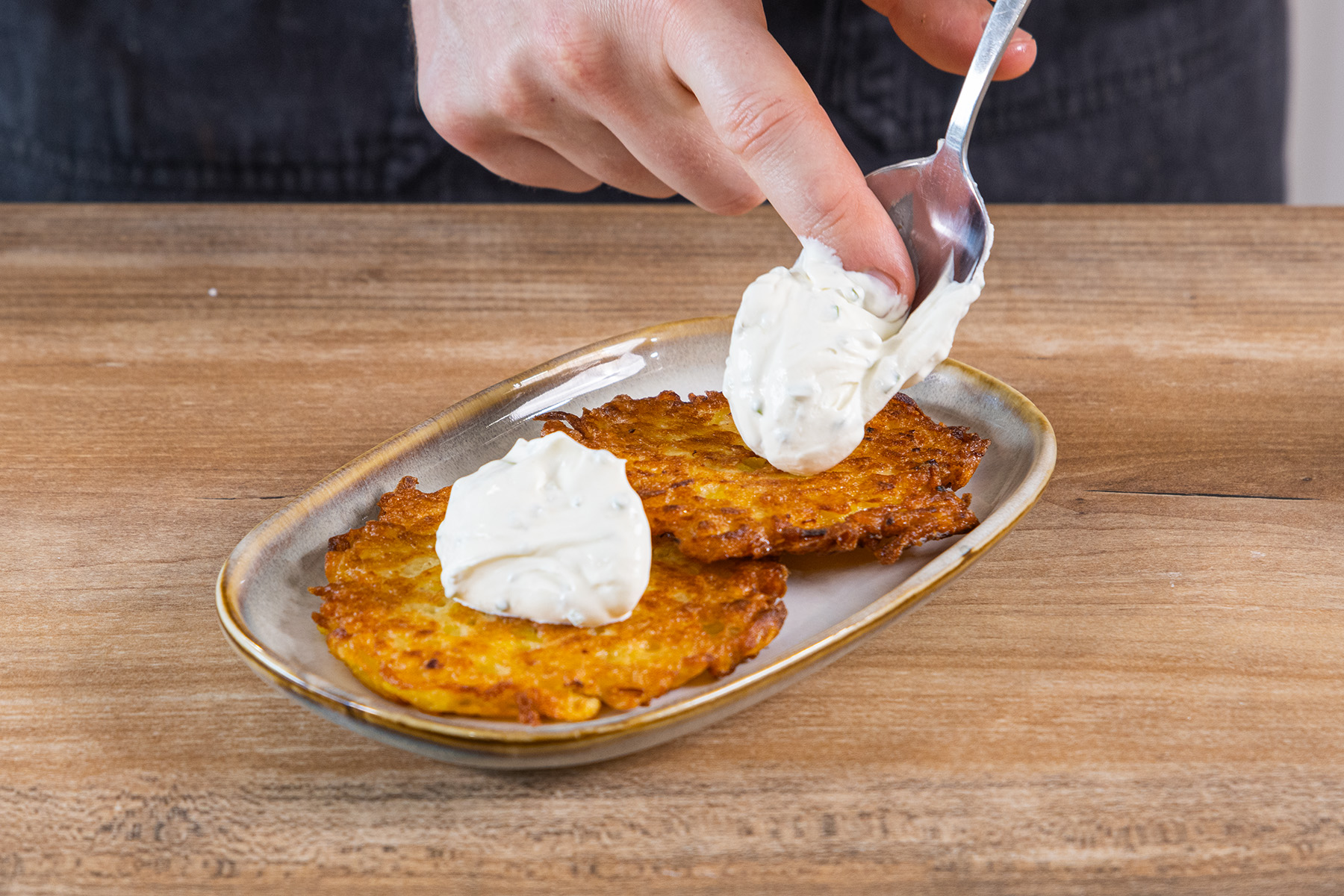 Crème fraîche auf den Kartoffelpuffern verteilen