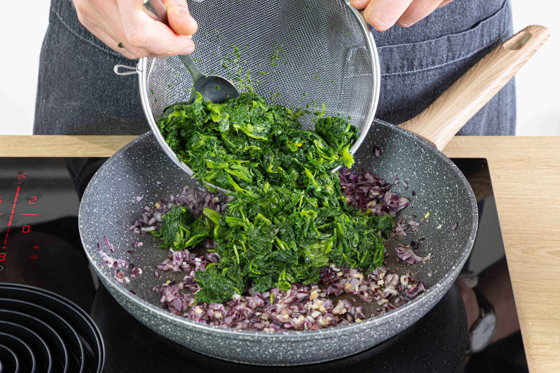 Spinat zu Zwiebel und Knoblauch geben