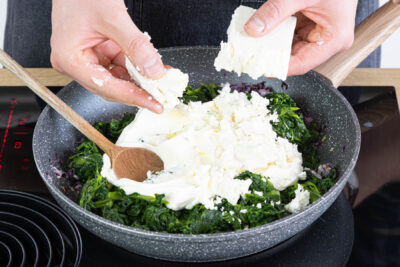 Cremé fraîche und Feta zum Spinat geben