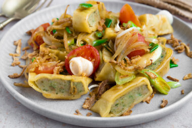 Die Maultaschen mit Zwiebeln und Petersilie garnieren.