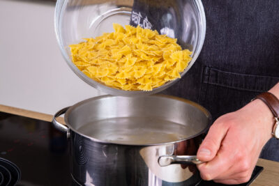 Farfalle in Salzwasser geben