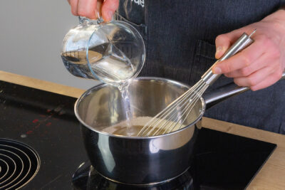 Wasser in einen Topf mit Zucker geben