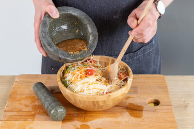 Dressing über den Papaya-Salat geben