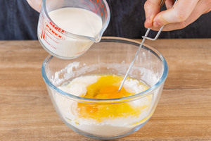 Milch in eine Schüssel mit Eiern und Mehl geben