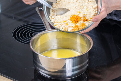 Keksbrösel zur Butter in den Topf geben