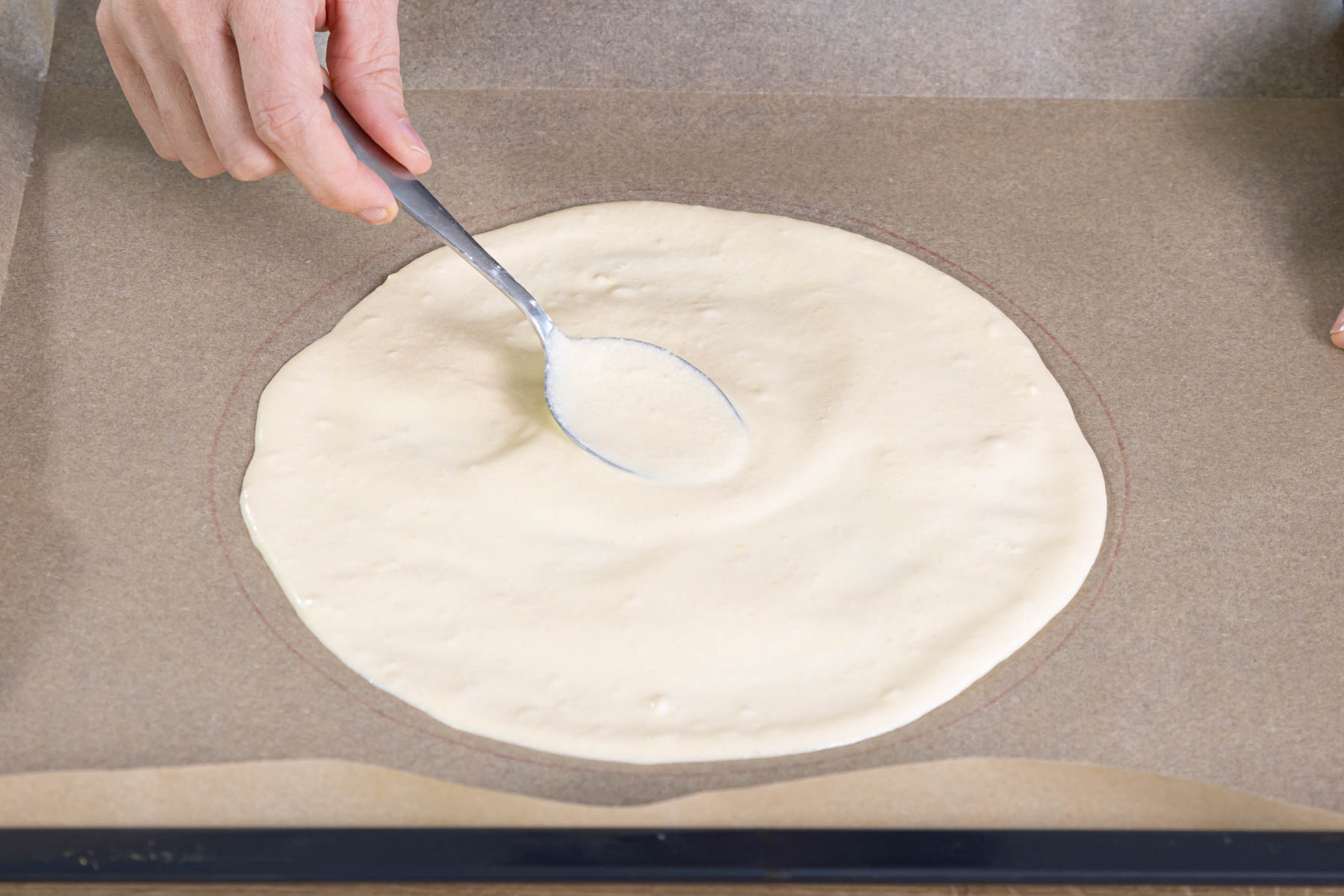 Biskuitteig auf das Backpapier streichen