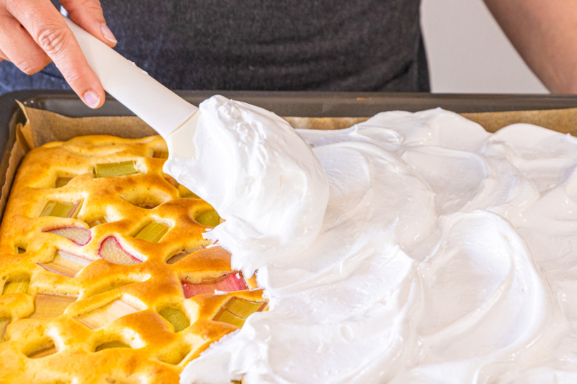 Baiser auf Rhabarberblechkuchen verteilen