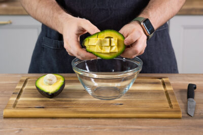 Die Avocado in kleine Würfel schneiden, die sich besser aus der Schale nehmen lassen.