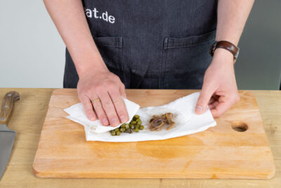 Kapern und Sardellen auf Krepppapier trocknen.