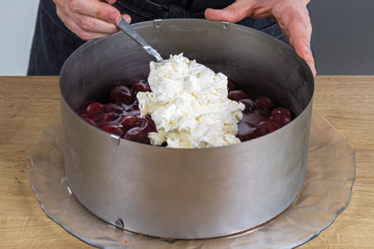 Sahnecreme auf der Kirschfüllung verteilen