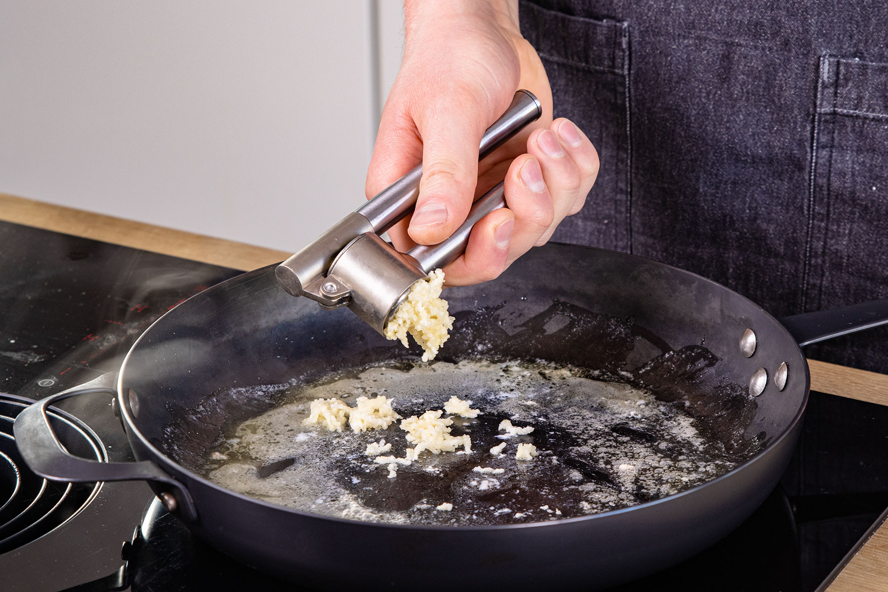 Knoblauch in Pfanne pressen
