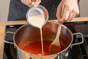 Sahne zur Tomatensuppe gießen