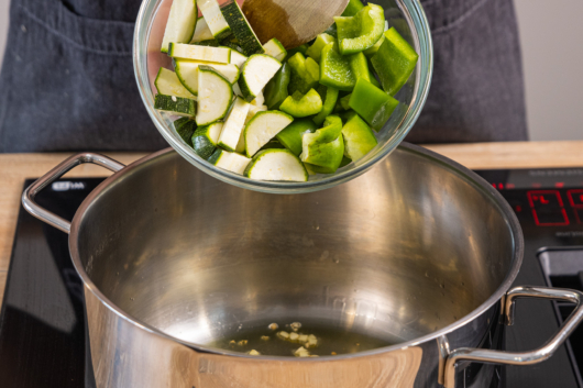 Zucchini und Paprika in den Topf geben