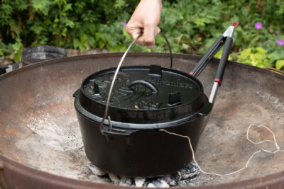 Den Dutch Oven auf die Briketts stellen und anschließend den Deckel mit Brickets bedecken.