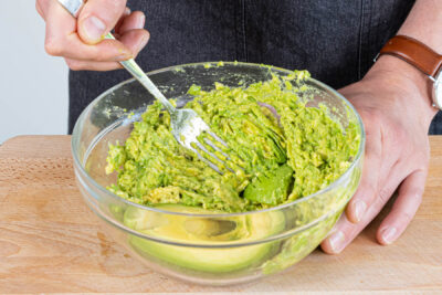 Avocado schälen, auslöffeln und mit einer Gabel zerdrücken