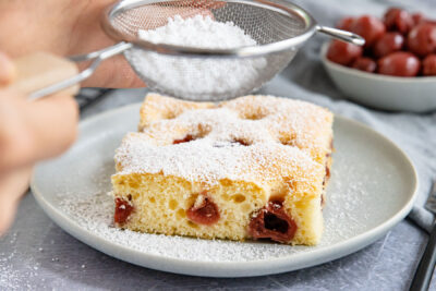 Blitzkuchen mit Sauerkirschen mit Puderzucker bestäuben