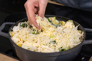 Blumenkohlauflauf mit Kartoffeln und Schinken mit Käse bestreuen