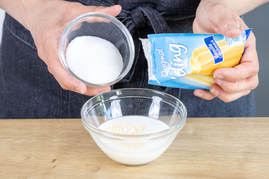 Zucker und Puddingpulver zur Milch geben