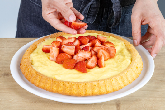 Erdbeeren auf den Pudding des Erdbeerkuchens geben