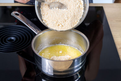 Kekskrümel zur geschmolzenen Butter geben