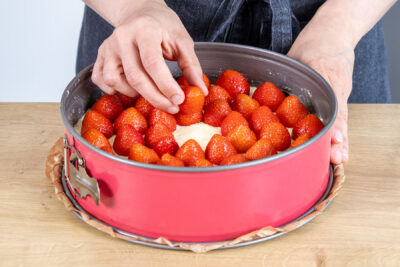 Erdbeeren auf die Puddingcreme des Erdbeerkuchens geben