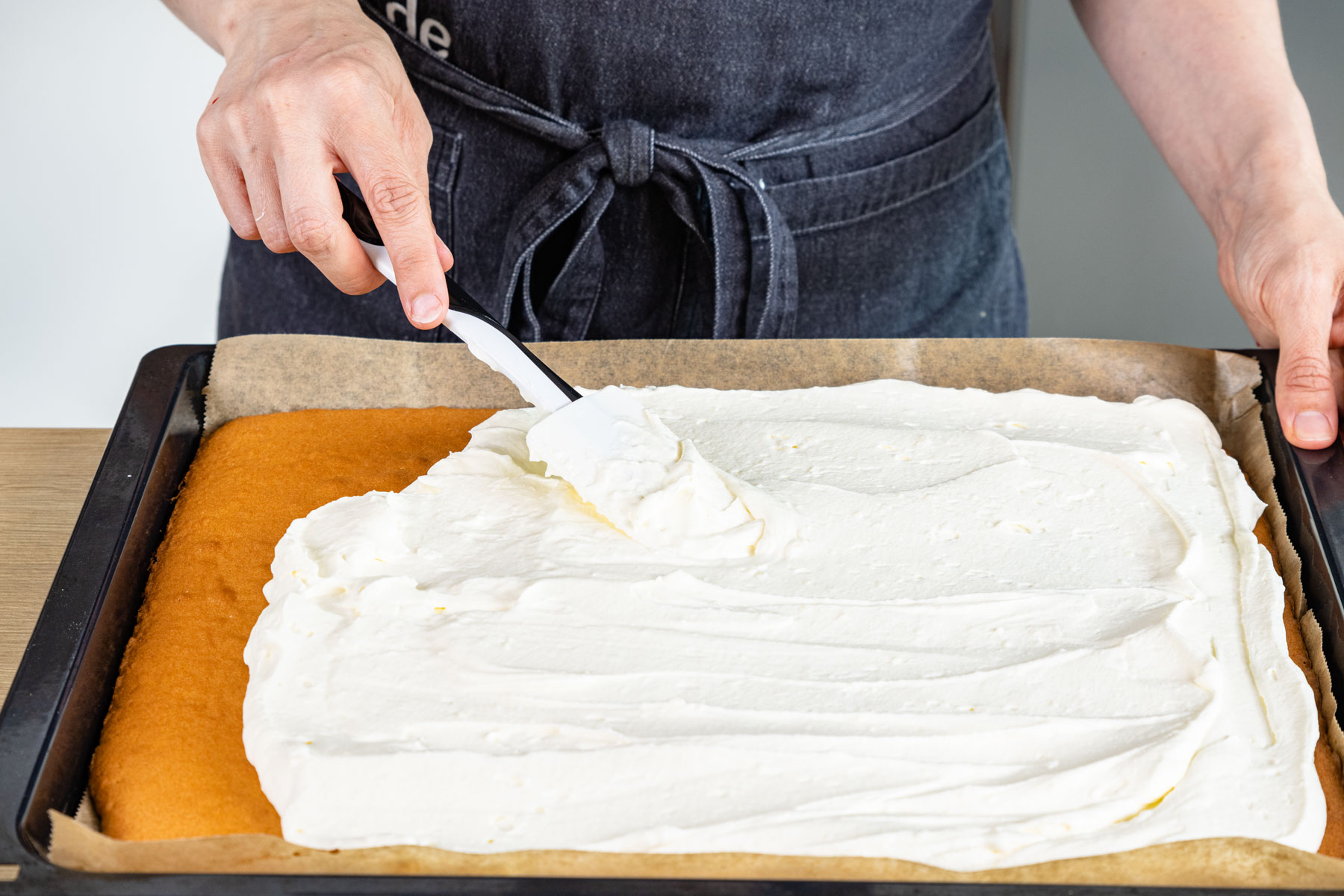 Sahnecreme auf Kuchenboden verteilen