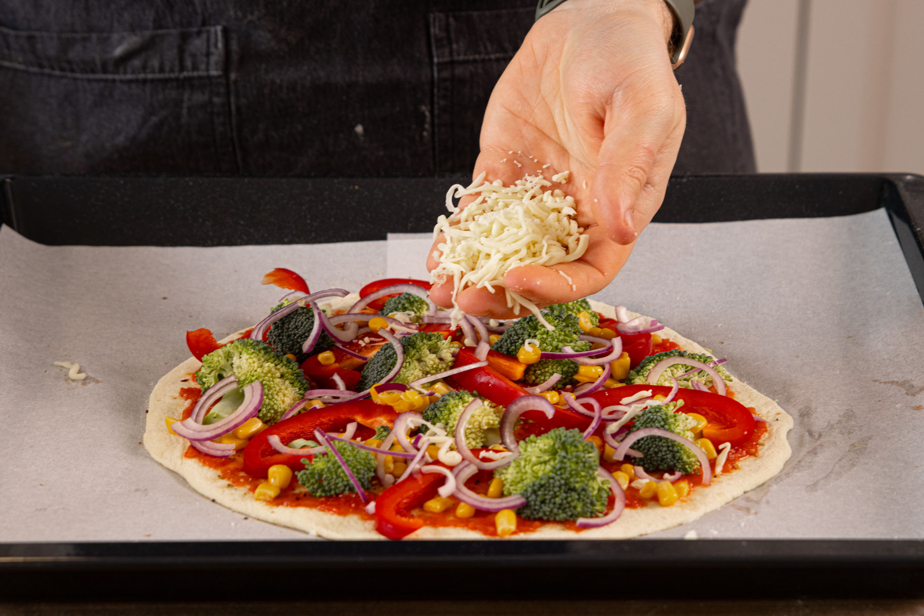 Käse über der Gemüsepizza verteilen.