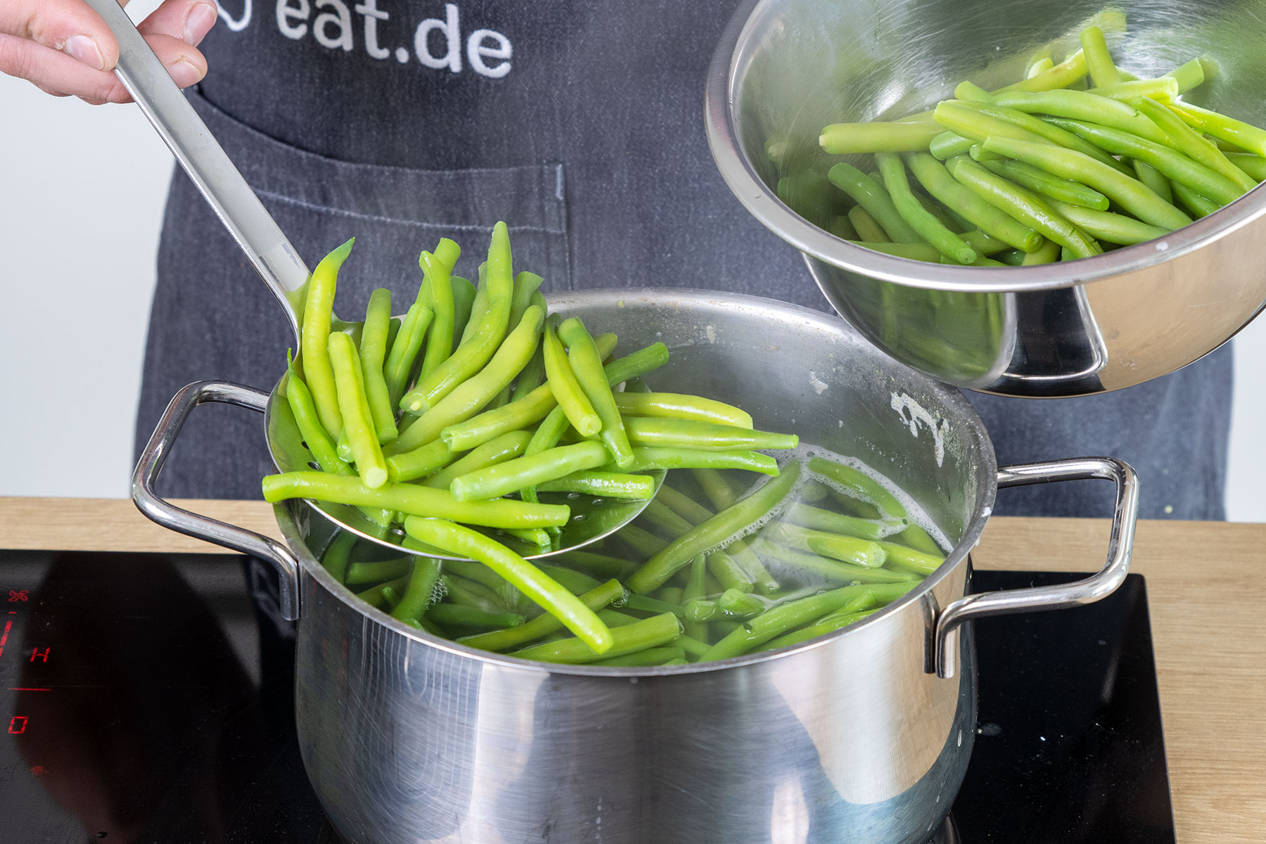 gekochte grüne Bohnen aus dem Wasser holen