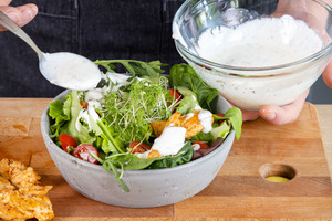Dressing über den Hähnchensalat geben