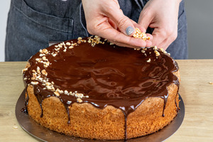 Haselnusskuchen ohne Mehl mit gehackten Nüssen dekorieren