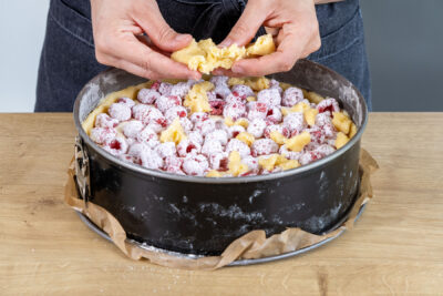 Mürbeteig über den Himbeerkuchen mit Quark streuen