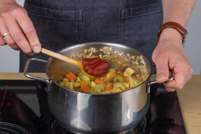 Das Tomatenmark mit in den Topf zum Gemüse geben.