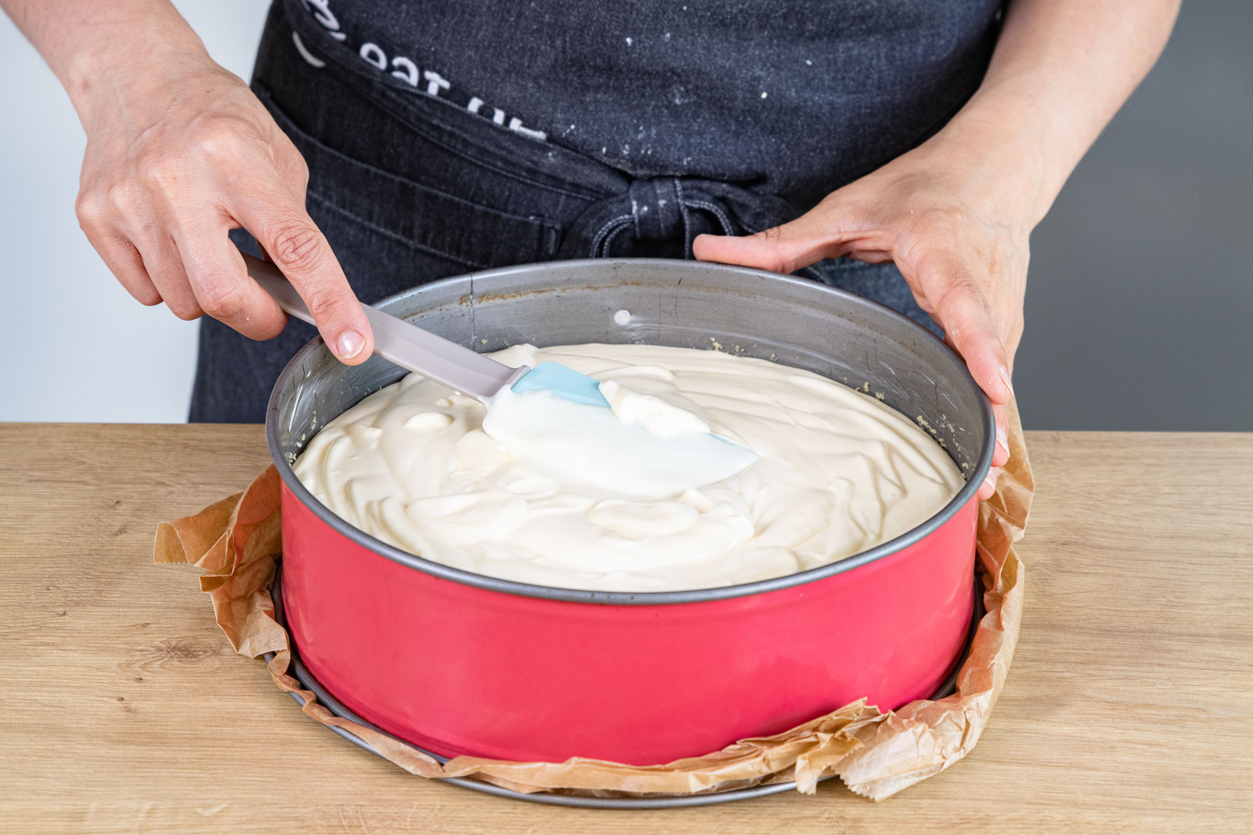 Käsekuchen-Masse auf Keksboden verteilen