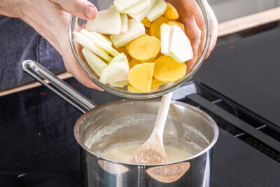 Kartoffeln und Kohlrabi in den Topf geben