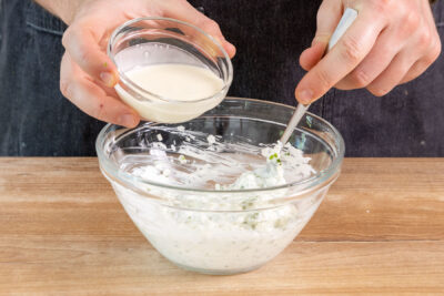 Sahne zu dem Knoblauch-Quark-Dip geben