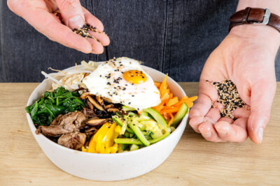 Koreanisches Bibimbap mit Sesam bestreuen