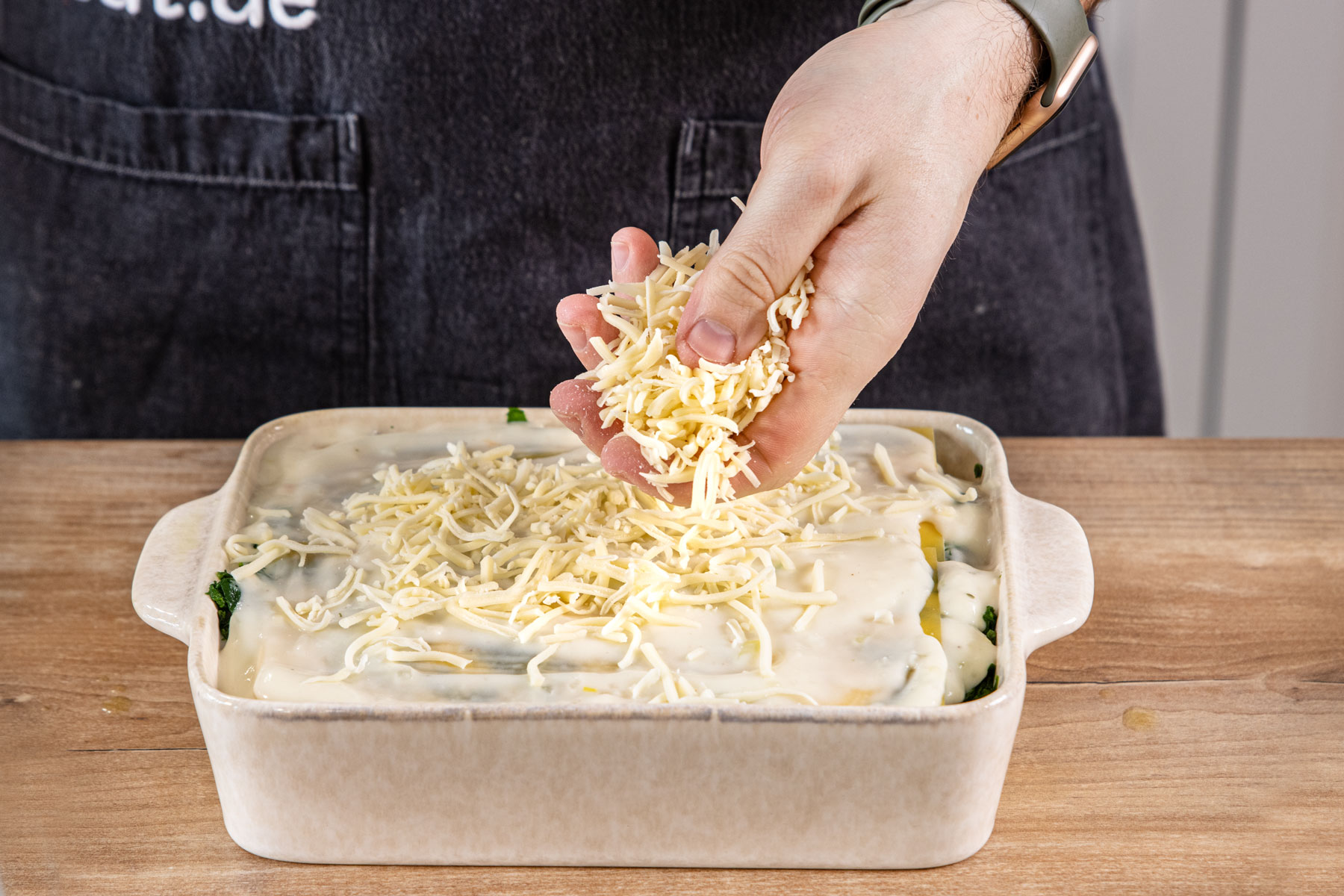 Lachslasagne mit Spinat mit Käse bestreuen