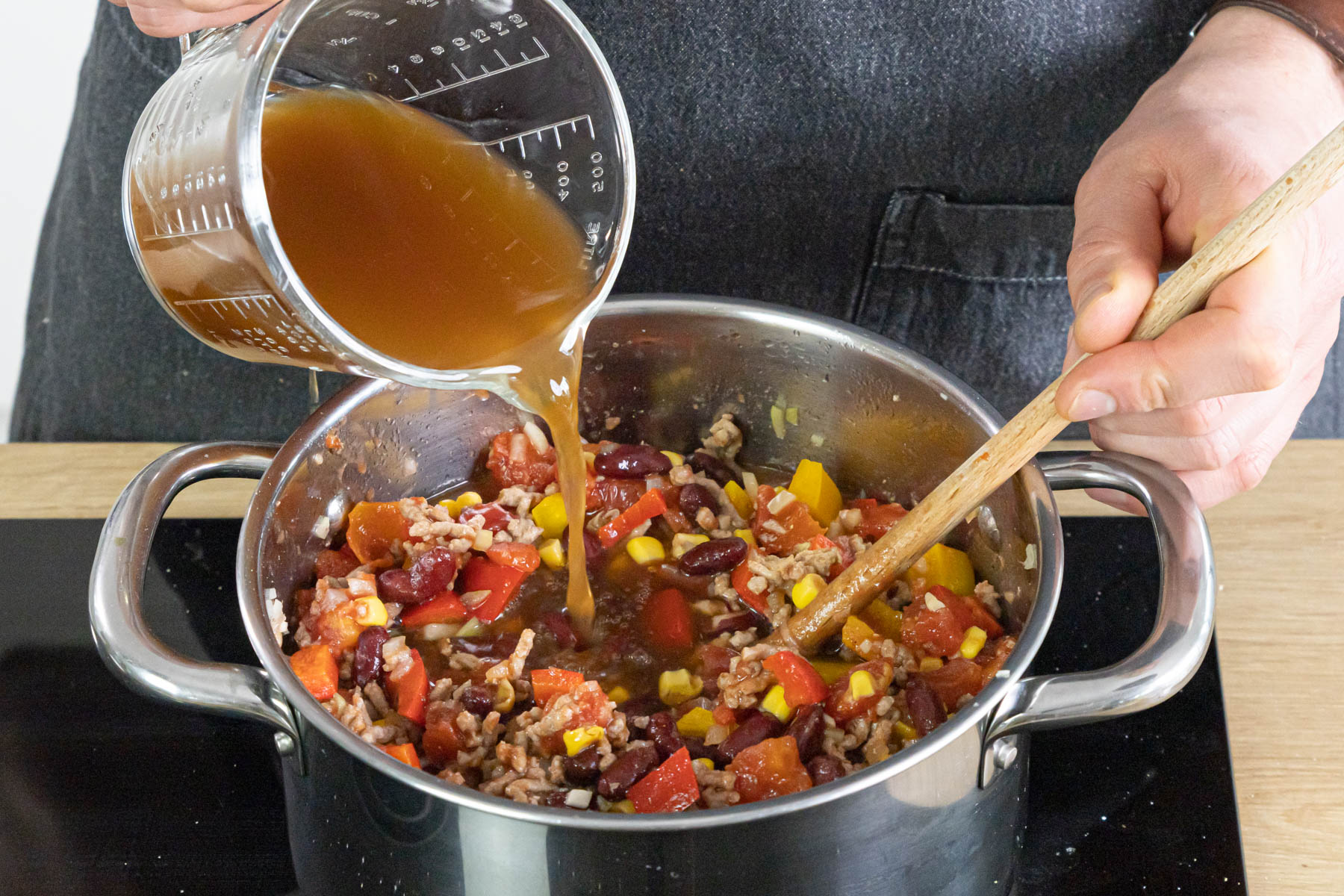 Brühe zur Mitternachtssuppe mit Hackfleisch gießen