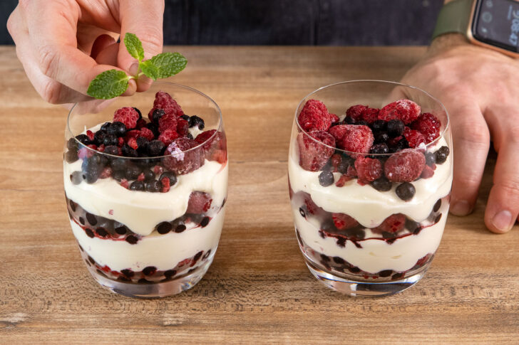 Nachtisch mit Mascarpone und gefrorenen Früchten mit Minze dekorieren