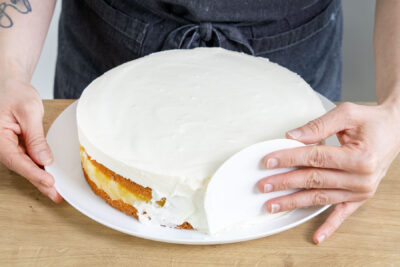 Ränder der Piña-Colada-Torte mit Kokos-Creme einstreichen