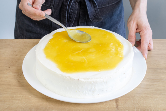Fruchtspiegel auf der Piña-Colada-Torte verteilen