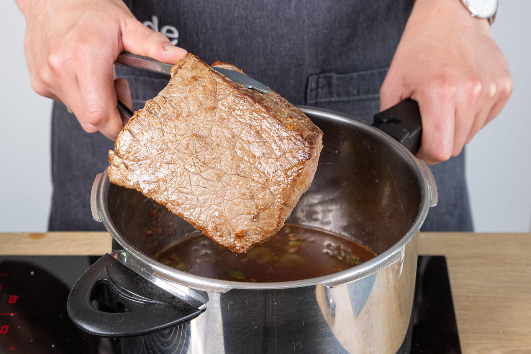 Rinderbraten in die Soße geben