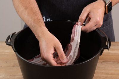 Den Dutch Oven mit Bacon auslegen.