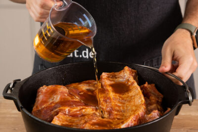 Rippchen nun in den Dutch Oven Schlichten und Saft darüber gießen.