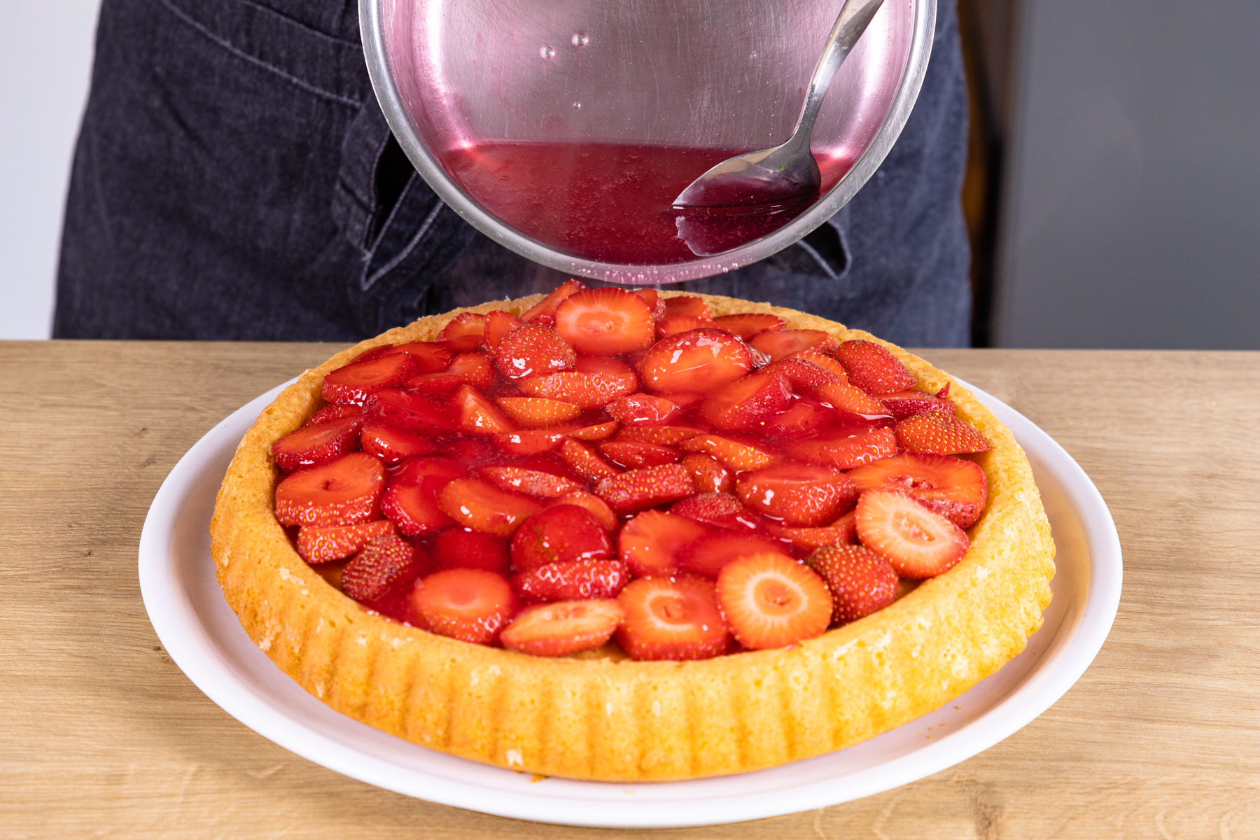 Tortenguss auf schnellem Erdbeerkuchen verteilen
