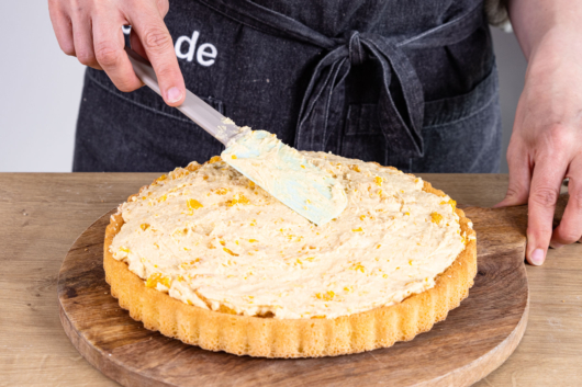Sahnecreme auf dem Tortenboden verstreichen