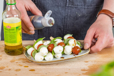 Tomaten-Mozzarella-Spieße mit Balsamico benetzen