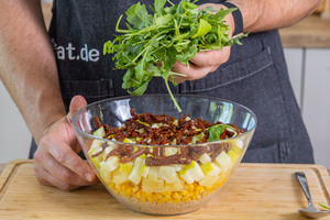 den Schichtsalat mit Rucola bedecken