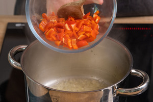 Paprika zu den Zwiebeln geben